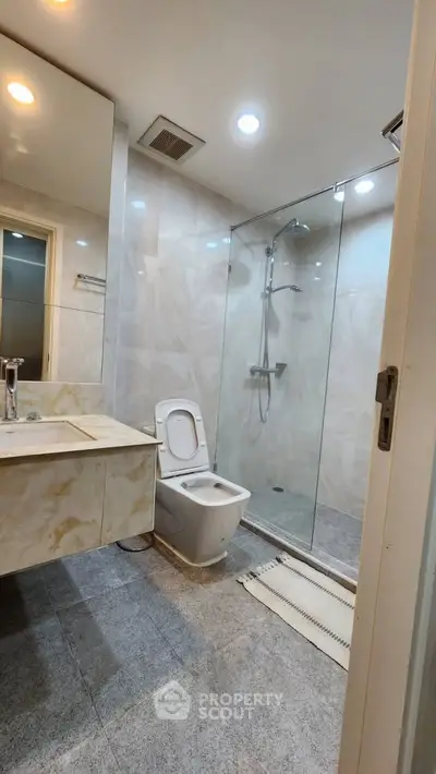 Modern bathroom with glass shower and marble sink in luxury apartment.
