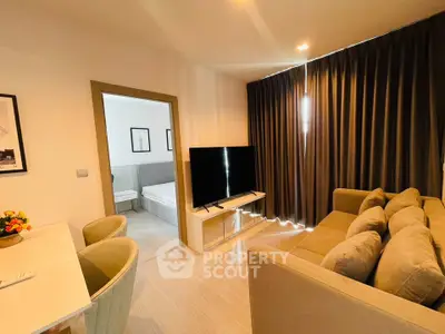 Modern living room with cozy sofa and large TV, adjacent to a bright bedroom.