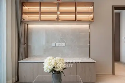 Modern living room with elegant built-in shelving and soft lighting, featuring a stylish flower arrangement.