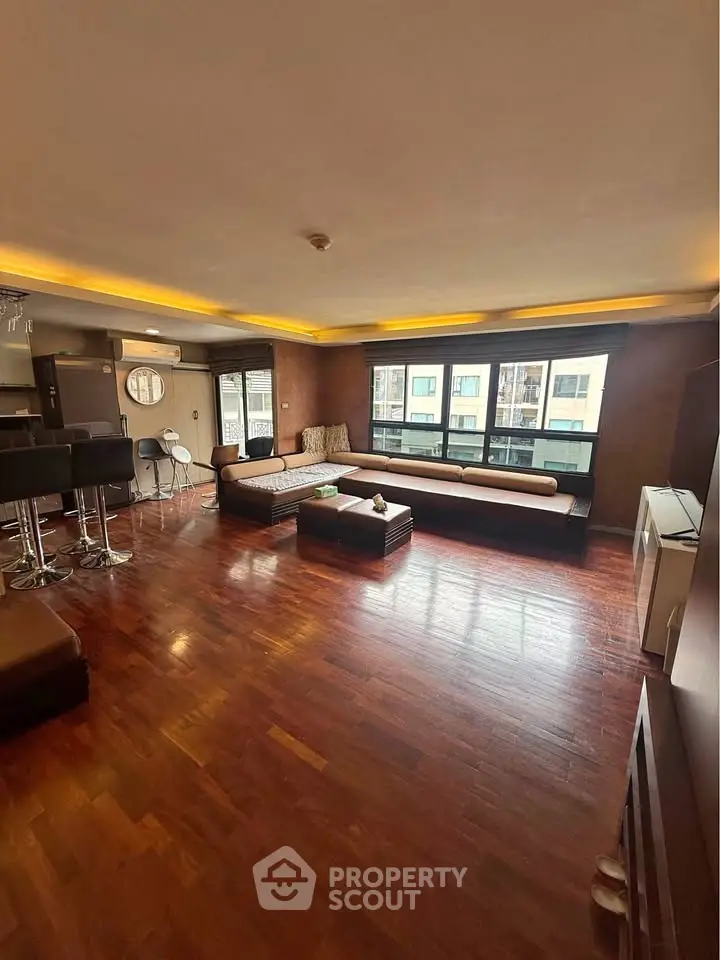 Spacious living room with hardwood floors and modern furnishings in a high-rise apartment.