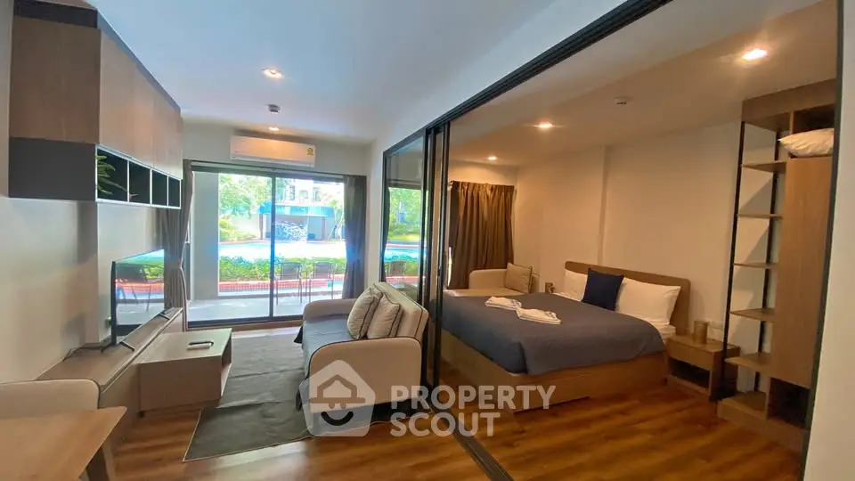 Modern studio apartment with glass partition, cozy living area, and pool view.