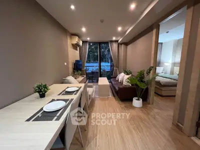 Modern open-plan living room with dining area and cozy bedroom view, featuring stylish decor and natural lighting.
