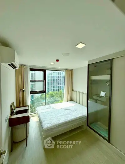 Modern bedroom with large window and city view, featuring a cozy bed and sleek furnishings.