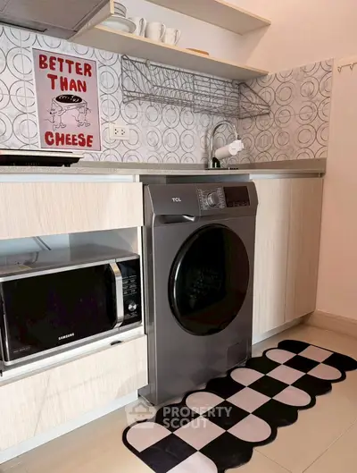 Modern kitchen with washing machine and microwave, stylish backsplash, and quirky wall art.