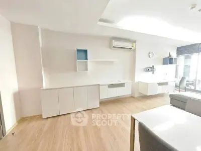 Spacious modern living room with sleek white cabinetry and wood flooring, featuring ample natural light.