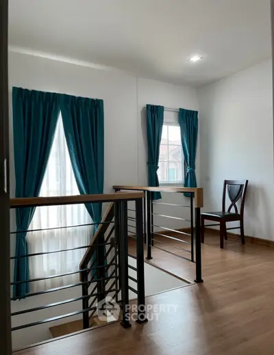 Bright and airy stairway with wooden floors and blue curtains in modern home.