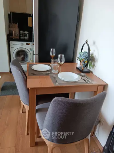 Cozy dining area with wooden table, chairs, and modern kitchen appliances in a stylish apartment.