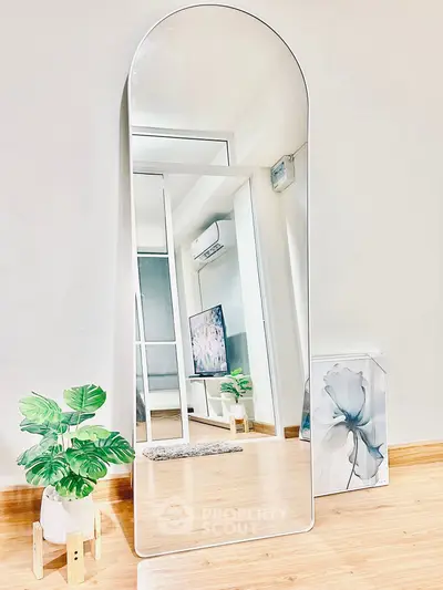 Modern living room with stylish mirror and wooden flooring, featuring a TV and air conditioning unit.