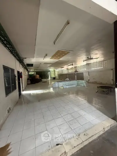 Spacious industrial warehouse with tiled flooring and ample natural light.