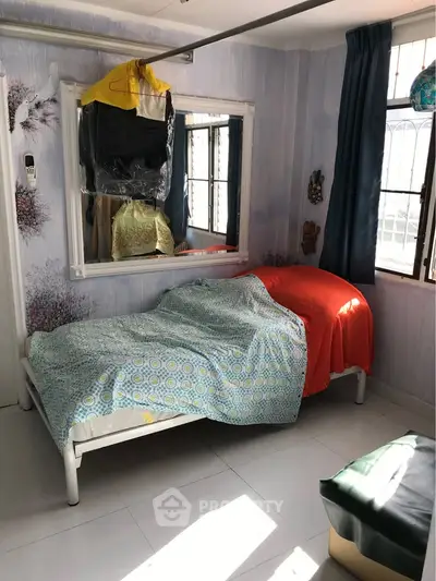 Cozy bedroom with natural light and decorative wall art, featuring a single bed and large window.