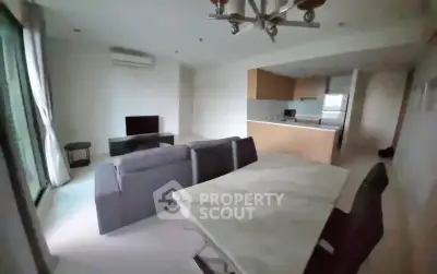 Modern open-plan living room with kitchen, featuring sleek furniture and natural light.