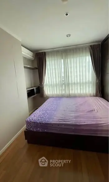 Cozy bedroom with large window and air conditioning, perfect for relaxation.