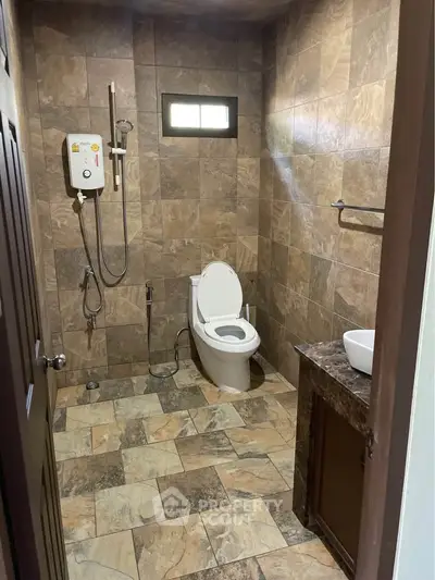 Modern bathroom with tiled walls and floor, featuring a toilet and shower area.