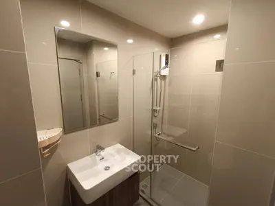 Modern bathroom with sleek design featuring a glass shower enclosure and stylish sink.