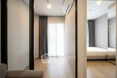 Modern bedroom with wooden flooring and large window, featuring a comfortable bed and stylish curtains.