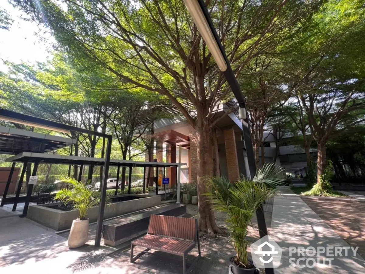 Modern building entrance with lush greenery and seating area