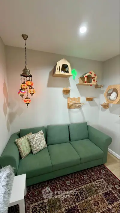 Charming living room with green sofa, decorative shelves, and colorful hanging lamp.