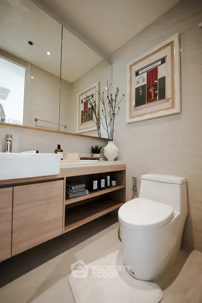 Modern bathroom with sleek fixtures and stylish decor, featuring a large mirror and elegant cabinetry.