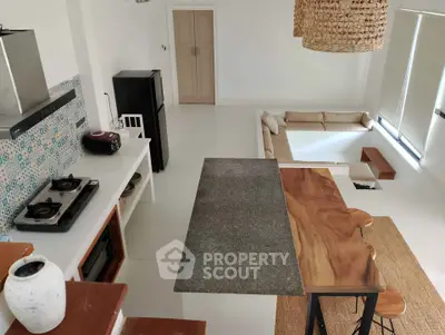 Stylish open-layout kitchen with modern appliances and cozy living area, featuring natural wood accents and ample lighting.