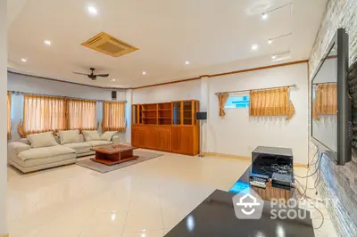 Spacious living room with gleaming tiled floors, elegant drapery, and ample natural light, featuring modern comforts and a cozy ambiance for family gatherings.