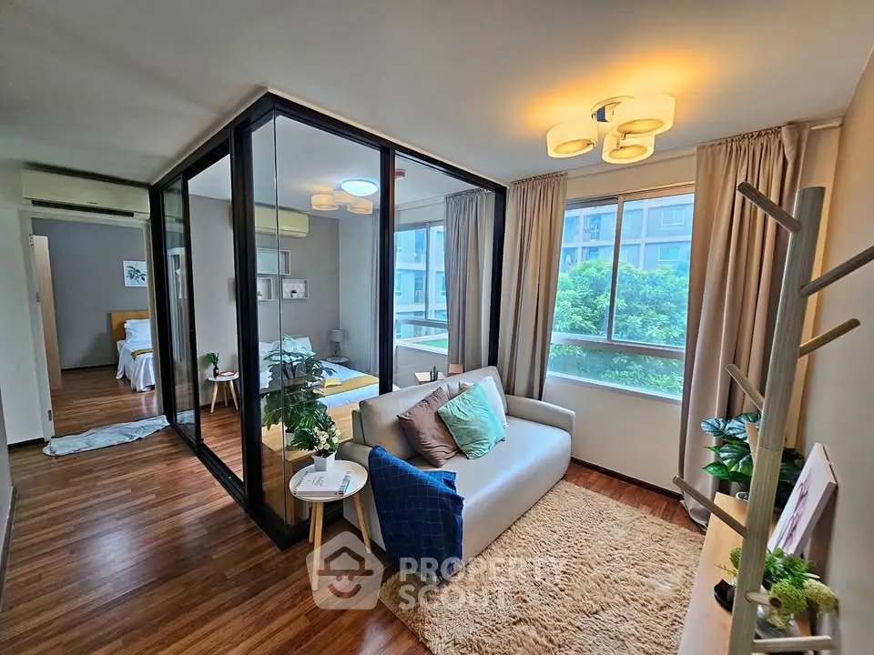 Modern living room with glass partition, cozy seating, and natural light in stylish apartment.