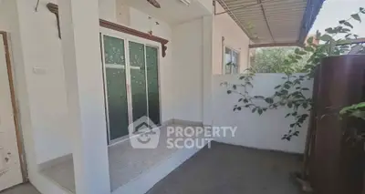 Charming small patio with sliding glass doors and partial roof cover, perfect for outdoor relaxation.