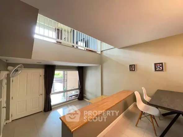Spacious modern living room with high ceiling and mezzanine, featuring elegant decor and natural light.
