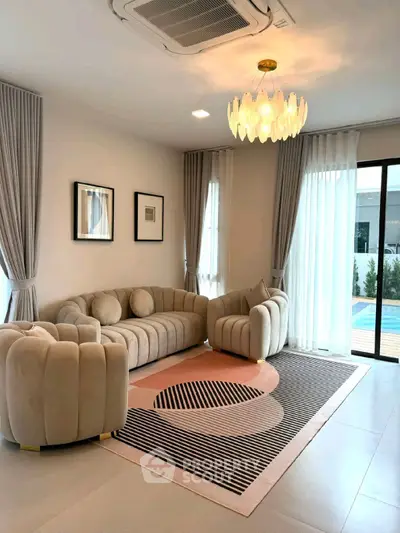 Elegant living room with modern furniture and pool view, featuring stylish lighting and large windows.