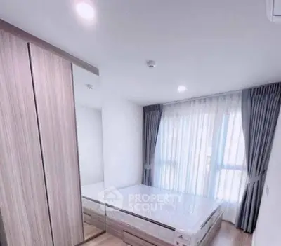 Modern bedroom with large window and stylish wardrobe in a bright apartment.