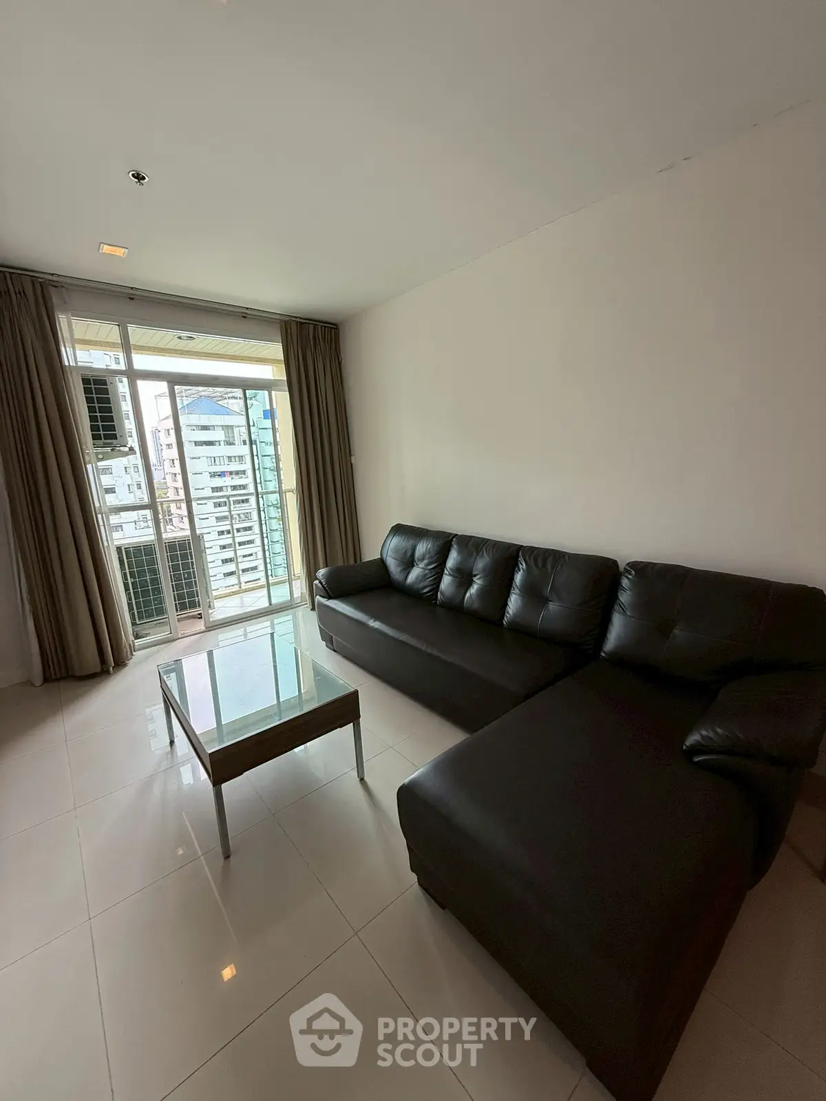 Modern living room with black leather sofa and city view balcony