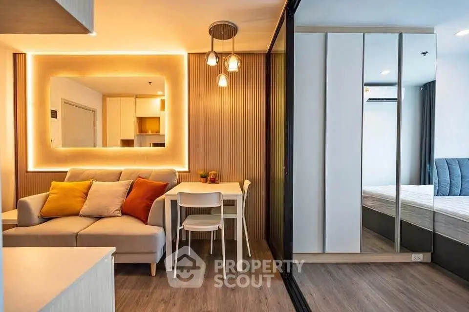 Modern living room with cozy sofa, stylish lighting, and adjacent bedroom in a chic apartment.