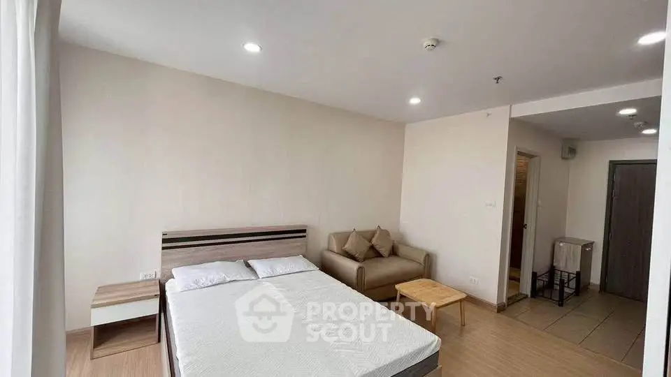 Spacious bedroom with modern decor and cozy seating area in a stylish apartment.