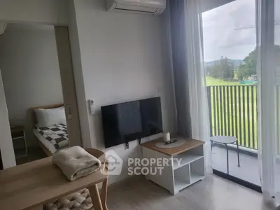Modern apartment living room with balcony view and cozy furnishings.