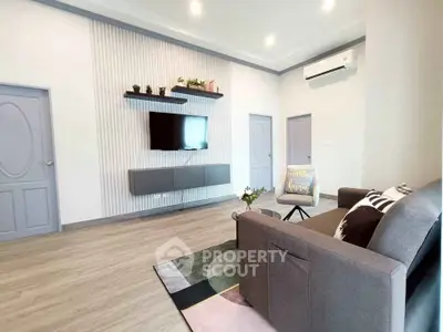 Modern living room with stylish decor and wall-mounted TV, featuring sleek furniture and elegant lighting.