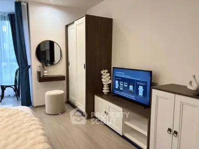 Modern bedroom with stylish furniture and TV, featuring elegant decor and natural light.