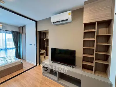 Modern living room with sleek TV unit and air conditioning, adjacent to a cozy bedroom with natural light.