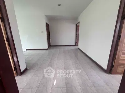 Spacious empty room with tiled flooring and wooden doors, ideal for customization.