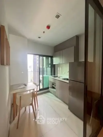 Modern kitchen with sleek cabinetry and dining area in a bright apartment.