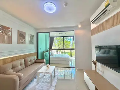 Modern living room with cozy sofa and view of bedroom through glass doors, featuring stylish decor and air conditioning.
