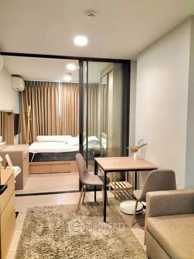 Modern studio apartment with cozy living area and glass partitioned bedroom, featuring stylish furniture and natural light.
