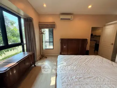 Spacious bedroom with large window and elegant wooden furniture