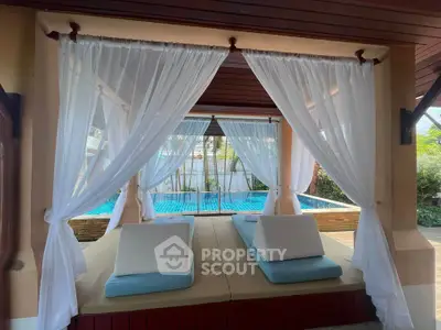Luxurious poolside cabana with elegant drapes and plush seating, perfect for relaxation and leisure.