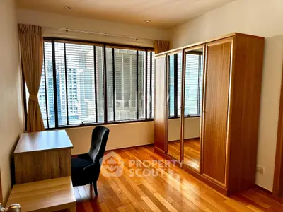 Spacious bedroom with wooden flooring and large windows offering city views.