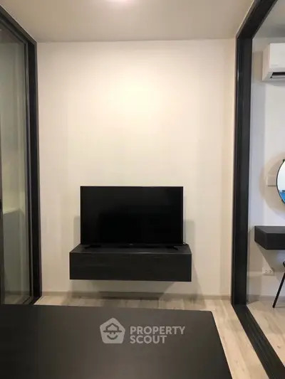 Sleek modern living room with wall-mounted TV, minimalist floating shelf, and large glass sliding door for ample natural light.