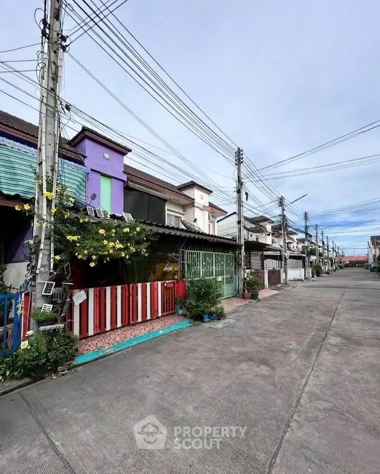 Charming row of colorful townhouses with vibrant facades and lush greenery in a serene neighborhood.