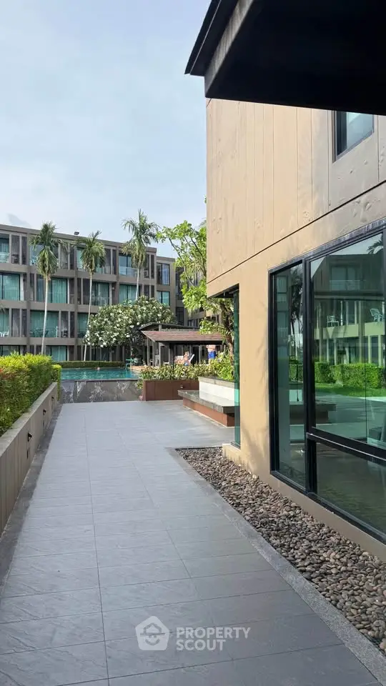 Modern apartment complex with lush greenery and spacious walkways, offering a serene living environment.
