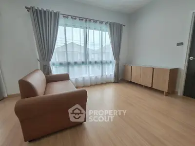 Spacious living room with modern sofa and natural light through large windows.