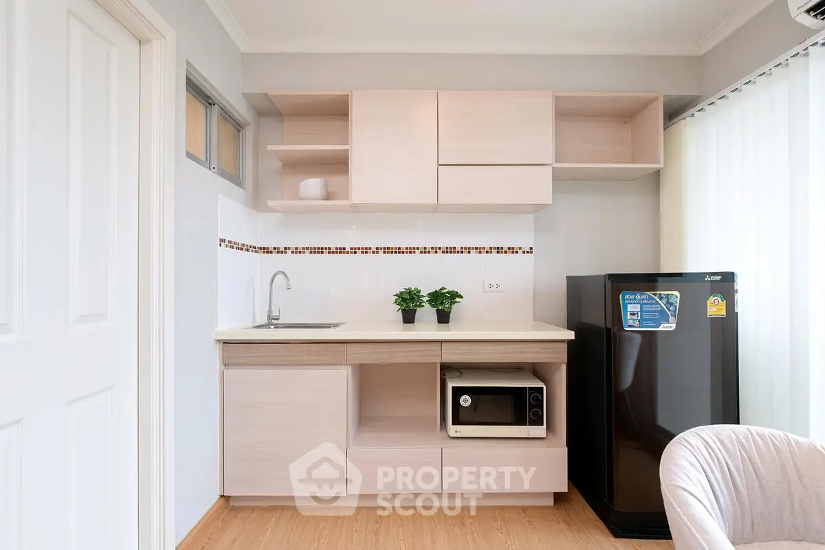 Modern compact kitchen with sleek cabinetry and appliances in a stylish apartment.