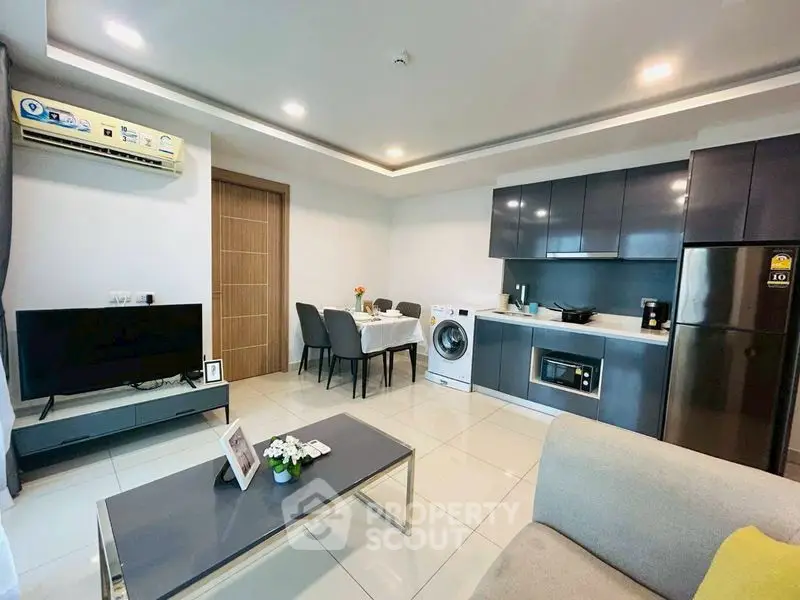 Modern open-layout living room with sleek kitchen and dining area, featuring stylish furniture and appliances.