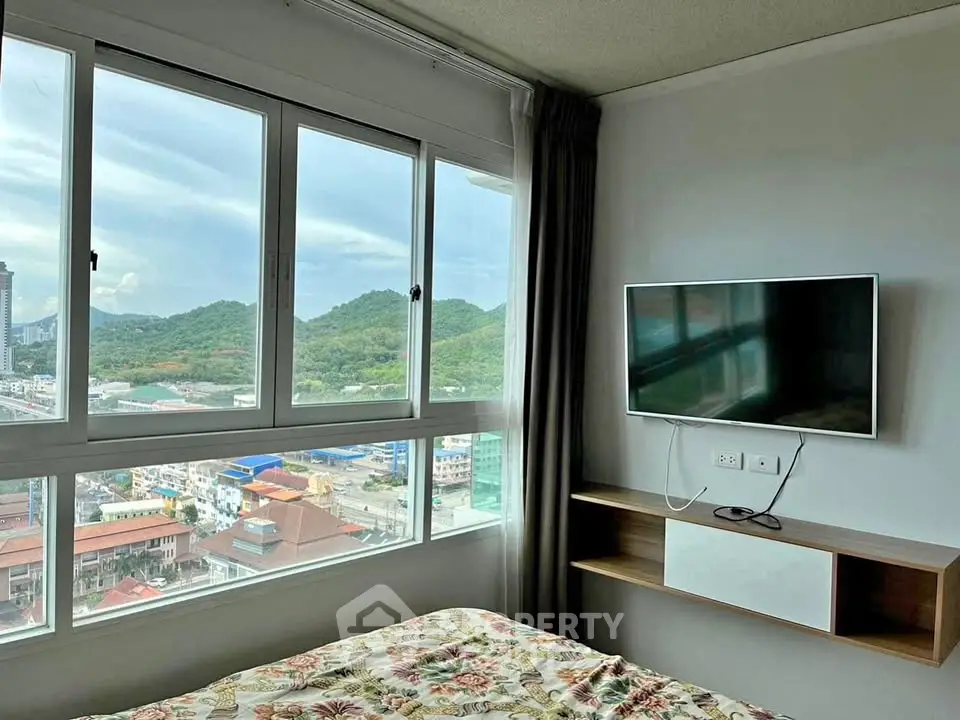 Modern bedroom with stunning mountain view and wall-mounted TV in high-rise apartment.